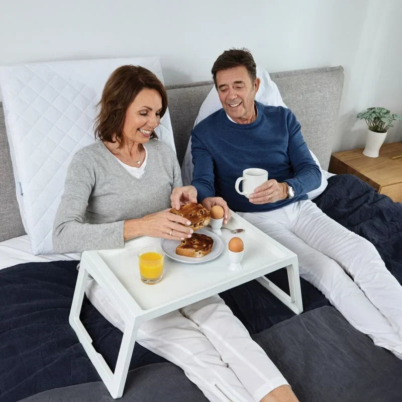 Older couple sitting up in bed with the TheraMed Adjusta Wedge