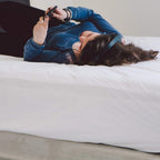 Woman resting on a bed made with the Conni Micro-Plush Waterproof Sheet (King)
