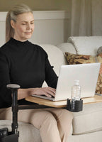 Woman using a laptop on the Independence Tray Table beside a sofa